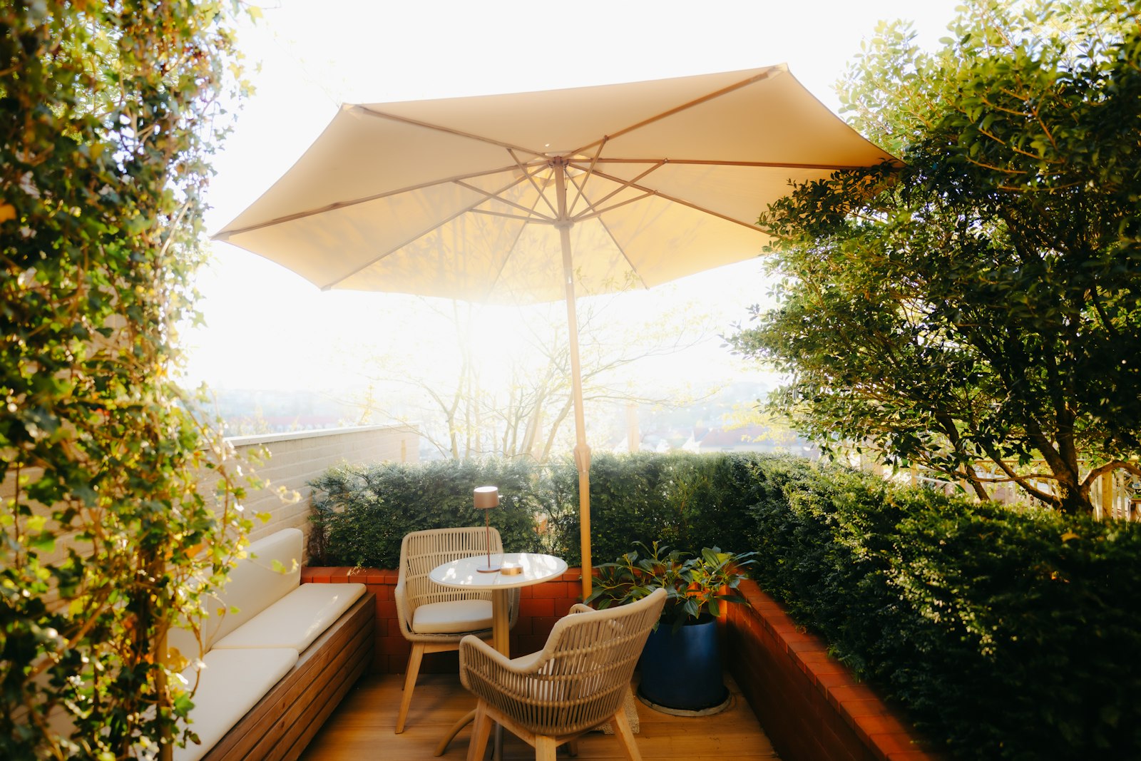 A sunny patio corner with an umbrella, bistro table, and chairs